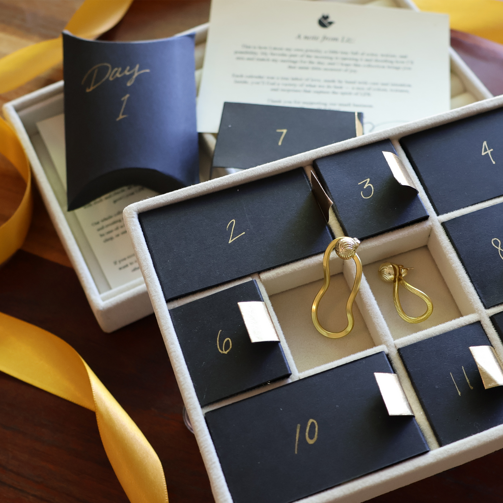 Advent calendar with gold earrings on a wooden surface