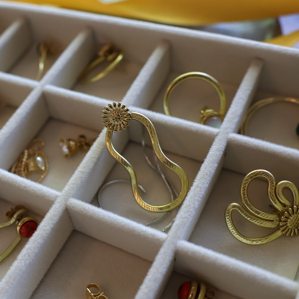 Gold earrings in a jewelry box with a yellow background