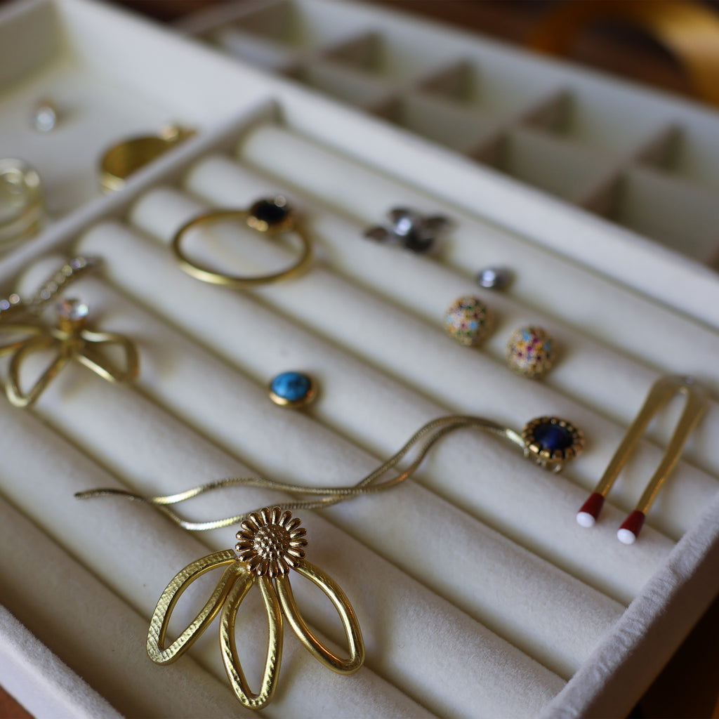 Jewelry display case with various earrings and a necklace on a white background