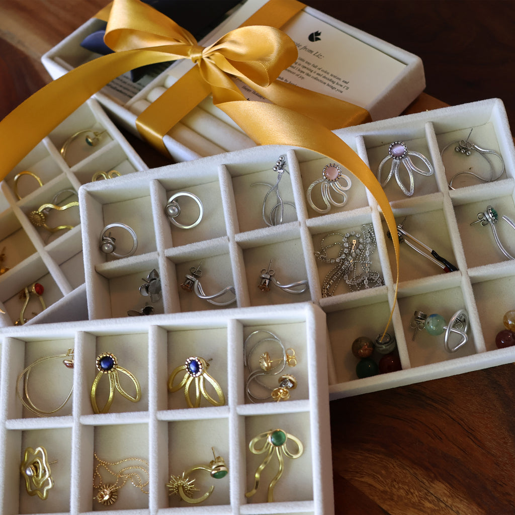 Jewelry box with various earrings and a yellow ribbon on a wooden surface